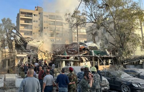 Emergency and security personnel gather at the site of strikes which hit a building next to the Iranian embassy in Syria's capital Damascus