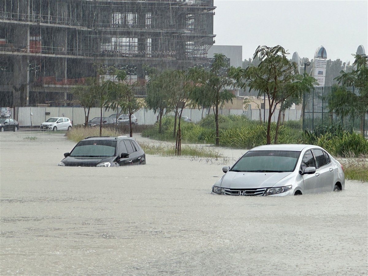 Men gesture as they try to tow a vehicle out of standing water in Dubai