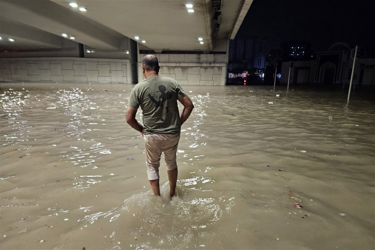 <i>Stringer/Anadolu/Getty Images via CNN Newsource</i><br/>People wade through a submerged street under a bridge after heavy rain in the United Arab Emirates on Tuesday.