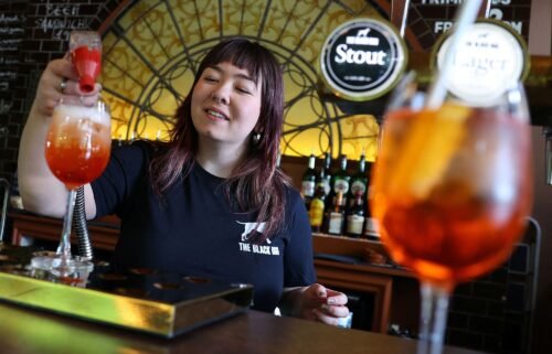 An employee at The Black Dog pub is pictured making an  'Aperol Spritz (Taylor's Version)' cocktail.