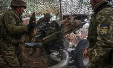 Ukrainian service members fire a L119 howitzer towards Russian troops