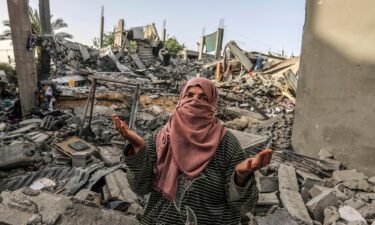 A Palestinian woman inspects a house that was destroyed by an Israeli bombing in Rafah