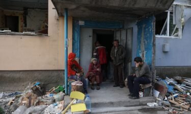 Local residents sit at the entrance of an apartment building destroyed by shelling in Ocheretyne on April 15.