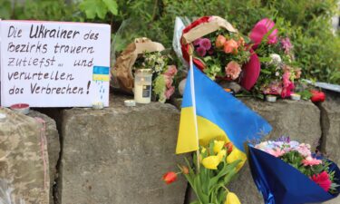 Flowers and a small Ukrainian flag are laid at a shopping center in Murnau