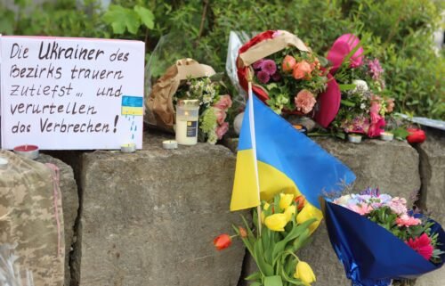 Flowers and a small Ukrainian flag are laid at a shopping center in Murnau