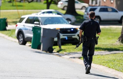 A Charlotte Mecklenburg police officer walks carrying a gun in the neighborhood where a shooting took place in Charlotte