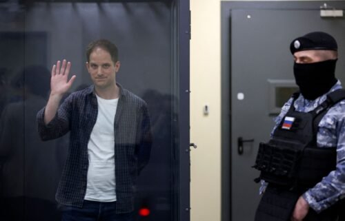 Wall Street Journal reporter Evan Gershkovich waves behind a glass wall of an enclosure for defendants in Moscow
