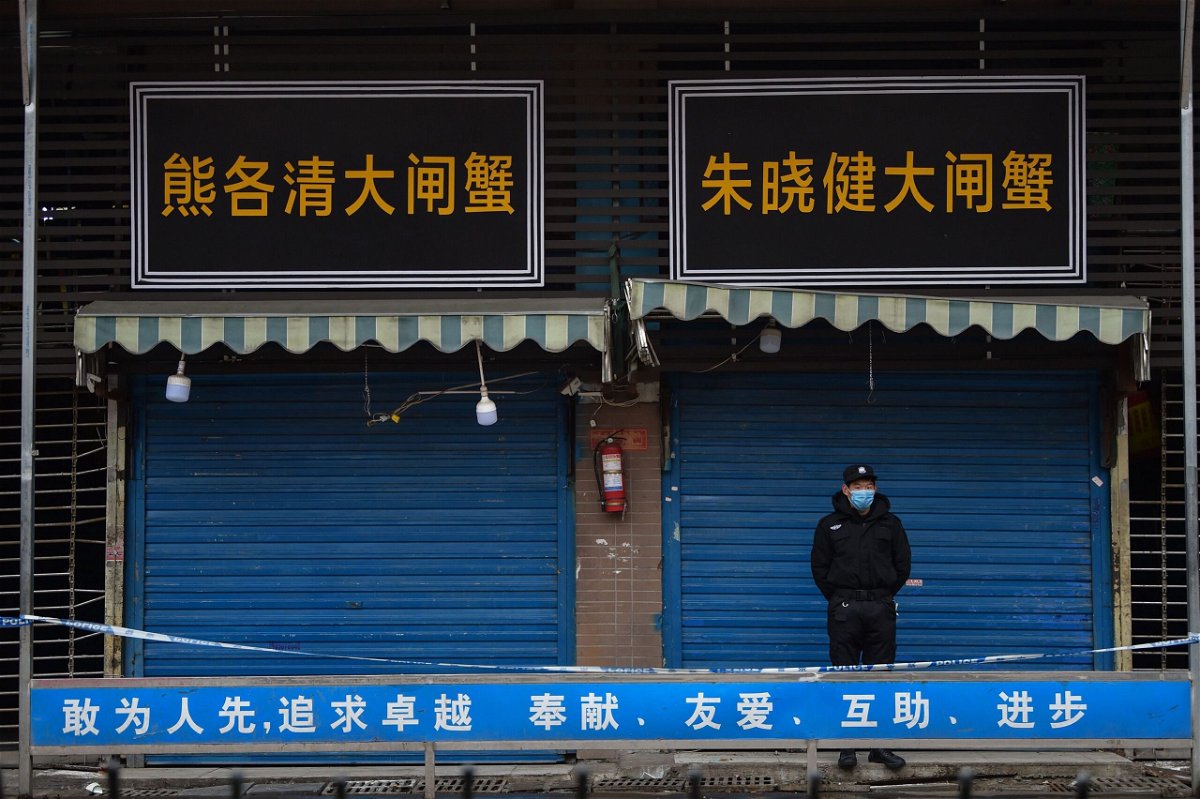 <i>Hector Retamal/AFP/Getty Images via CNN Newsource</i><br/>A security guard stands outside a wet market in Wuhan linked to some of the earliest known cases of Covid-19.