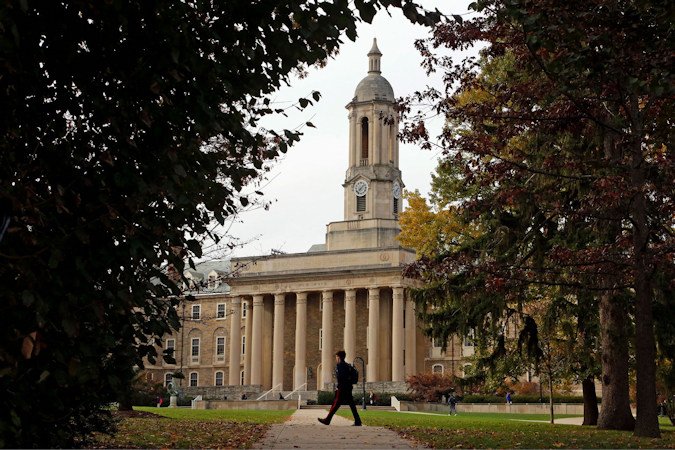 In this November 2017 file photo, people walk by Old Main on the Penn State University main campus in State College, Pennsylvania. Many students are stuck in limbo as they wait for delayed financial aid award letters.