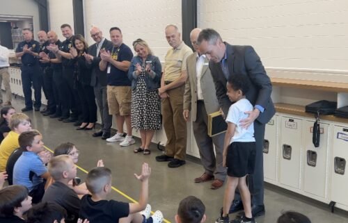 Superintendent Steve Wood congratulates second grader Trey Lewis for alerting others when a classmate had a severe allergic reaction to a granola bar.