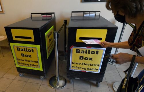 A voter puts a mail-in ballot in a ballot box at the Clark County Election Department