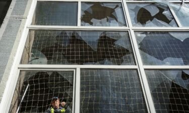 A worker removes shards of glass from a broken window in Kharkiv
