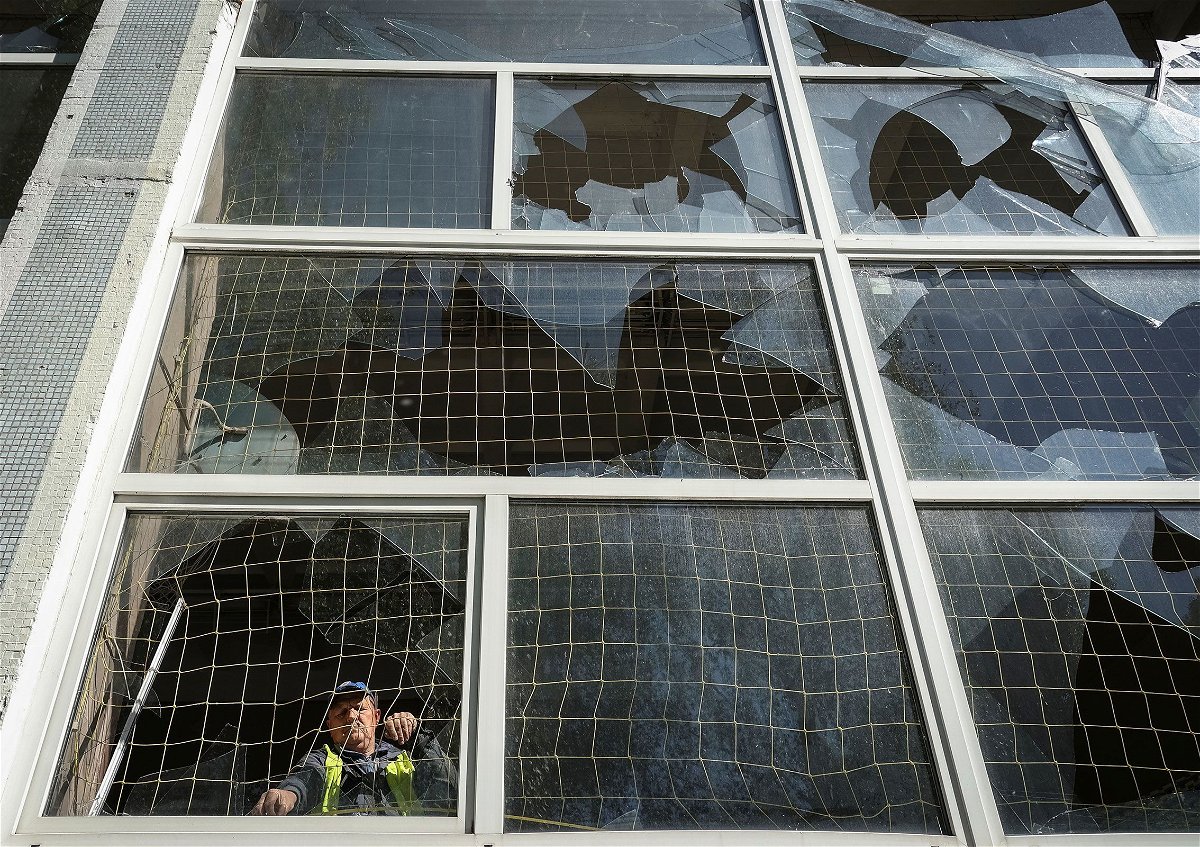 <i>Sofiia Gatilova/Reuters via CNN Newsource</i><br/>A worker removes shards of glass from a broken window in Kharkiv