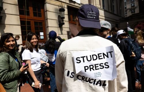 A Columbia Journalism student journalist shows off their sign as they cover the events at Hamilton Hall at Columbia University on April 30