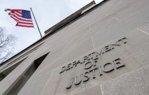 The US flag flies above a sign marking the US Department of Justice headquarters building on January 20