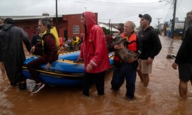 Residents and a dog are evacuated from a flooded area in the city center of São Sebastião do Cai
