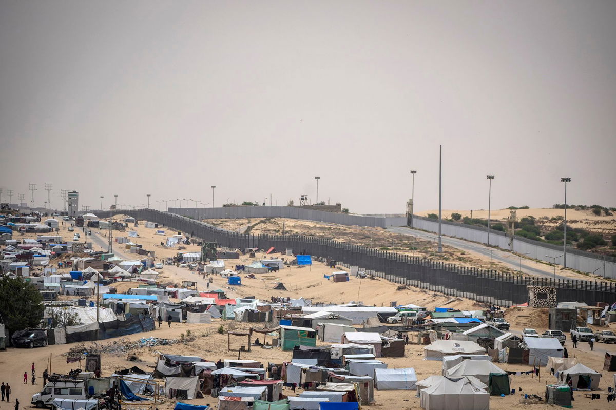 <i>Abdel Kareem Hana/AP via CNN Newsource</i><br/>Palestinians displaced by the Israeli air and ground offensive on the Gaza Strip walk through a makeshift tent camp in Rafah on the border with Egypt
