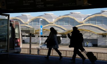 Travelers run to a waiting Metro train across from a terminal at Ronald Reagan Washington National Airport in Arlington