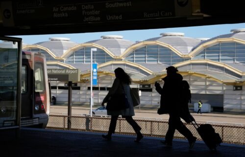 Travelers run to a waiting Metro train across from a terminal at Ronald Reagan Washington National Airport in Arlington