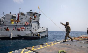 A U.S. Army Soldier tosses a line to an Army tug vessel from the Roll-On