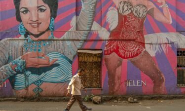 A man walks past a mural portraying Bollywood Indian actresses Asha Parekh and Helen