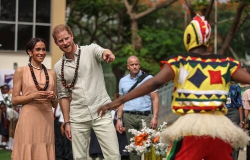 The Duke and Duchess of Sussex are welcomed to the Lightway Academy in Abuja by dancers on Friday.