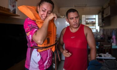 Katiane Mello (L) and her husband James Vargas cry before leaving their flooded home in Eldorado do Sul