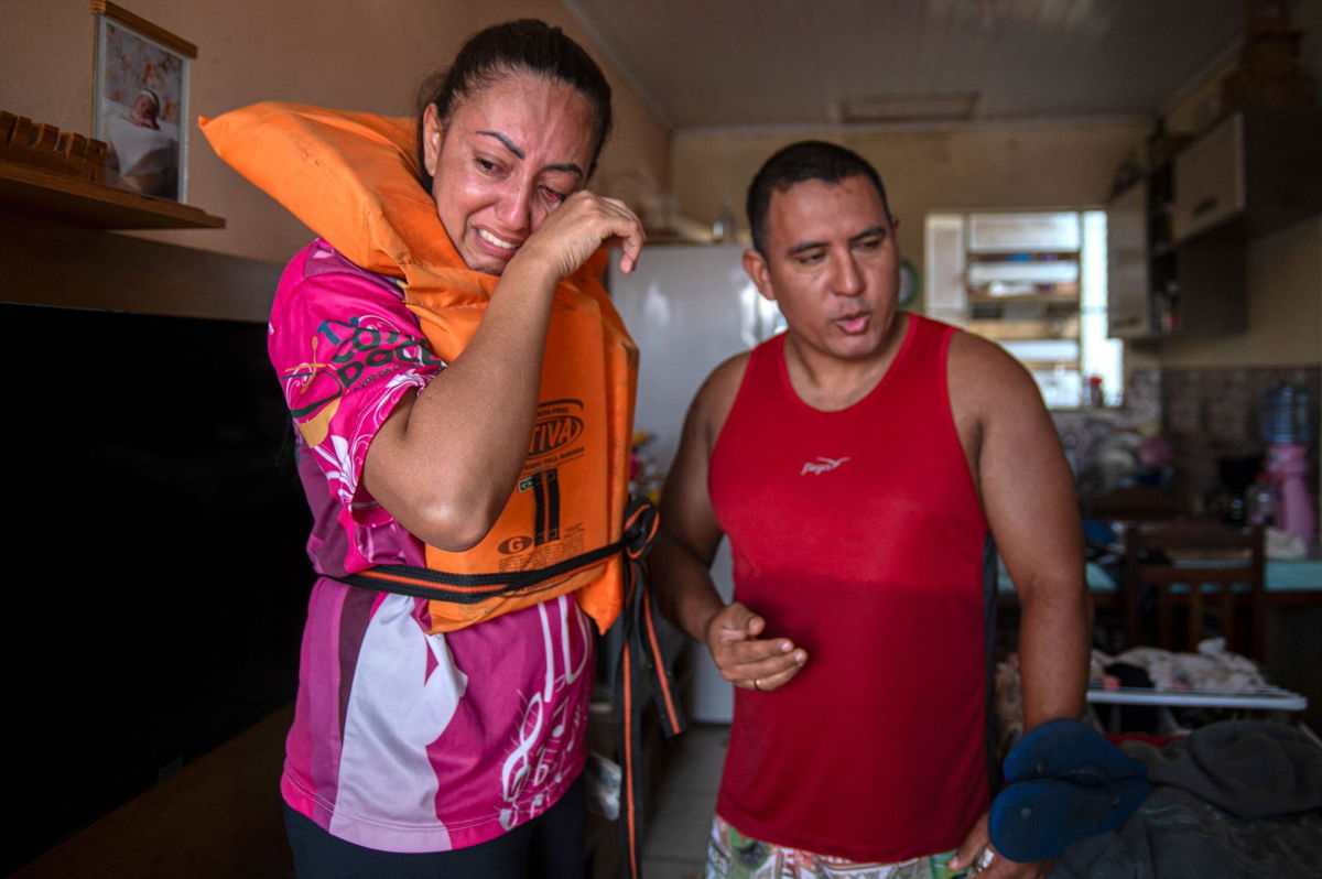 <i>Carlos Fabal/AFP/Getty Images via CNN Newsource</i><br/>Katiane Mello (L) and her husband James Vargas cry before leaving their flooded home in Eldorado do Sul