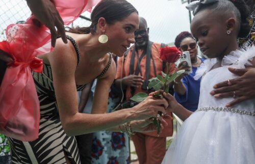Meghan receives flowers from a girl upon her arrival  for an exhibition sitting volleyball match at Nigeria Unconquered.