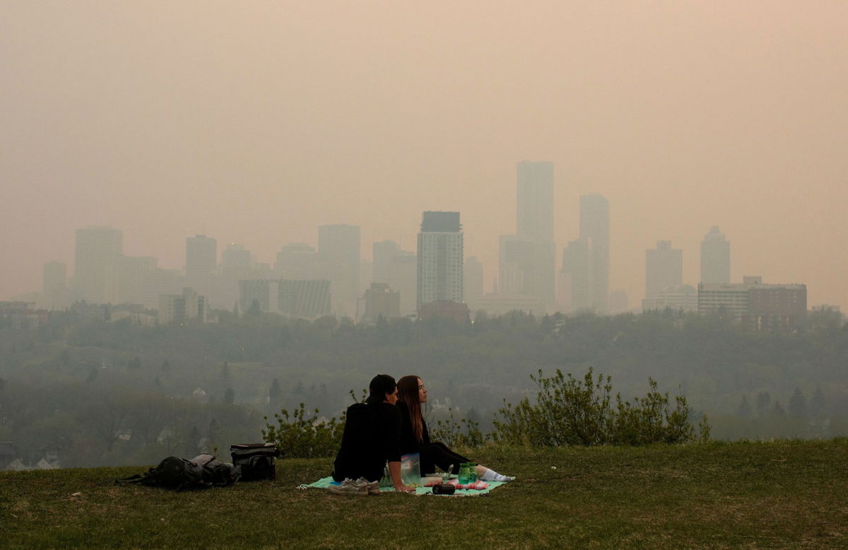 <i>Jason Franson/The Canadian Press/AP via CNN Newsource</i><br/>Smoke from wildfires blankets the city as a couple has a picnic in Edmonton