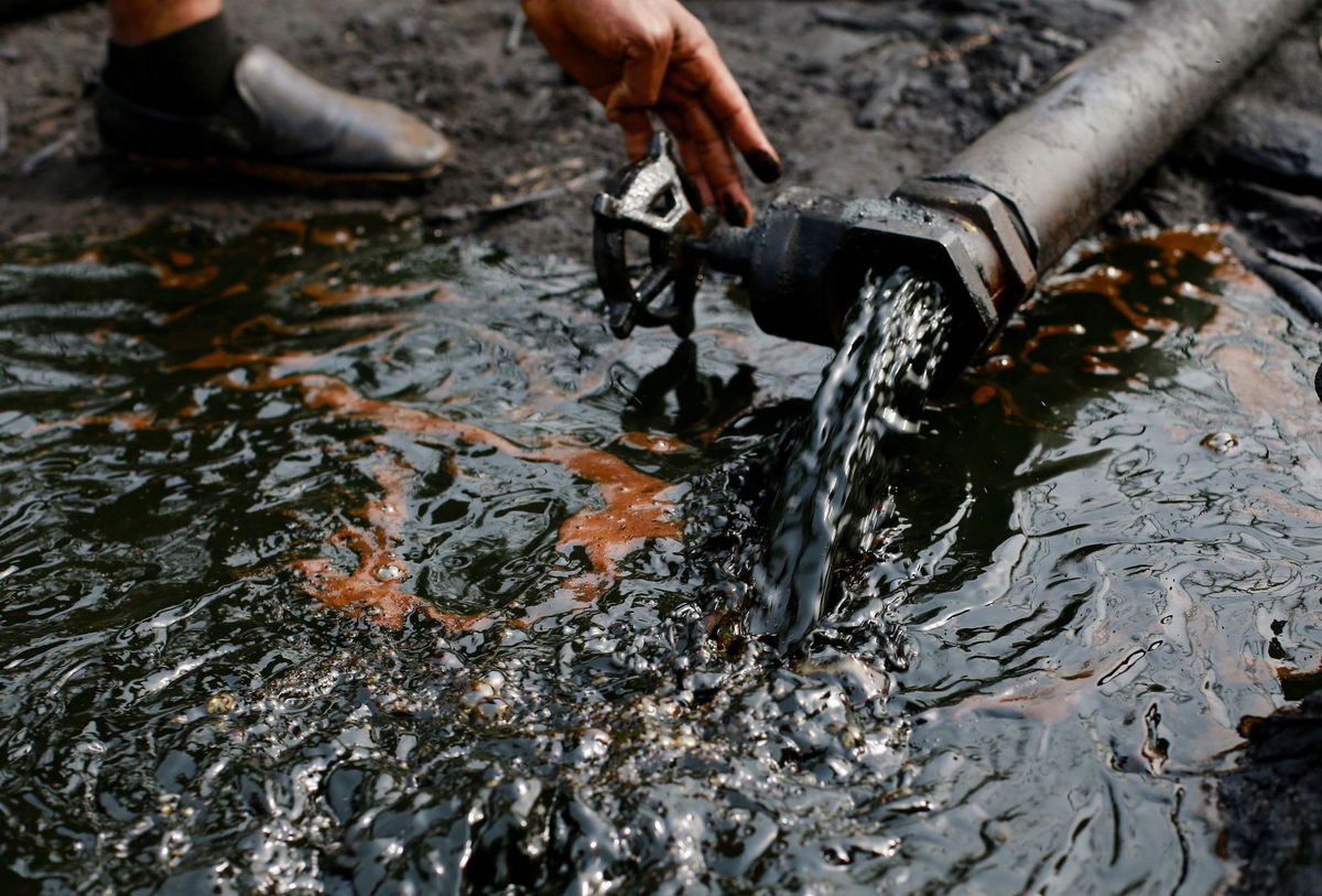 <i>Afolabi Sotunde/Reuters via CNN Newsource</i><br/>A person operates a tap of crude oil during the destruction of an illegal camp