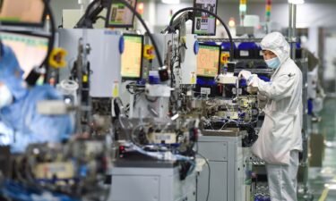 Employees operate machines at a dust-free workshop of a semiconductor factory on March 1