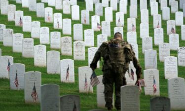 A US Army Old Guard soldier places a flag at a headstone during the annual 'Flags In' event ahead of Memorial Day at Arlington National Cemetery in Arlington