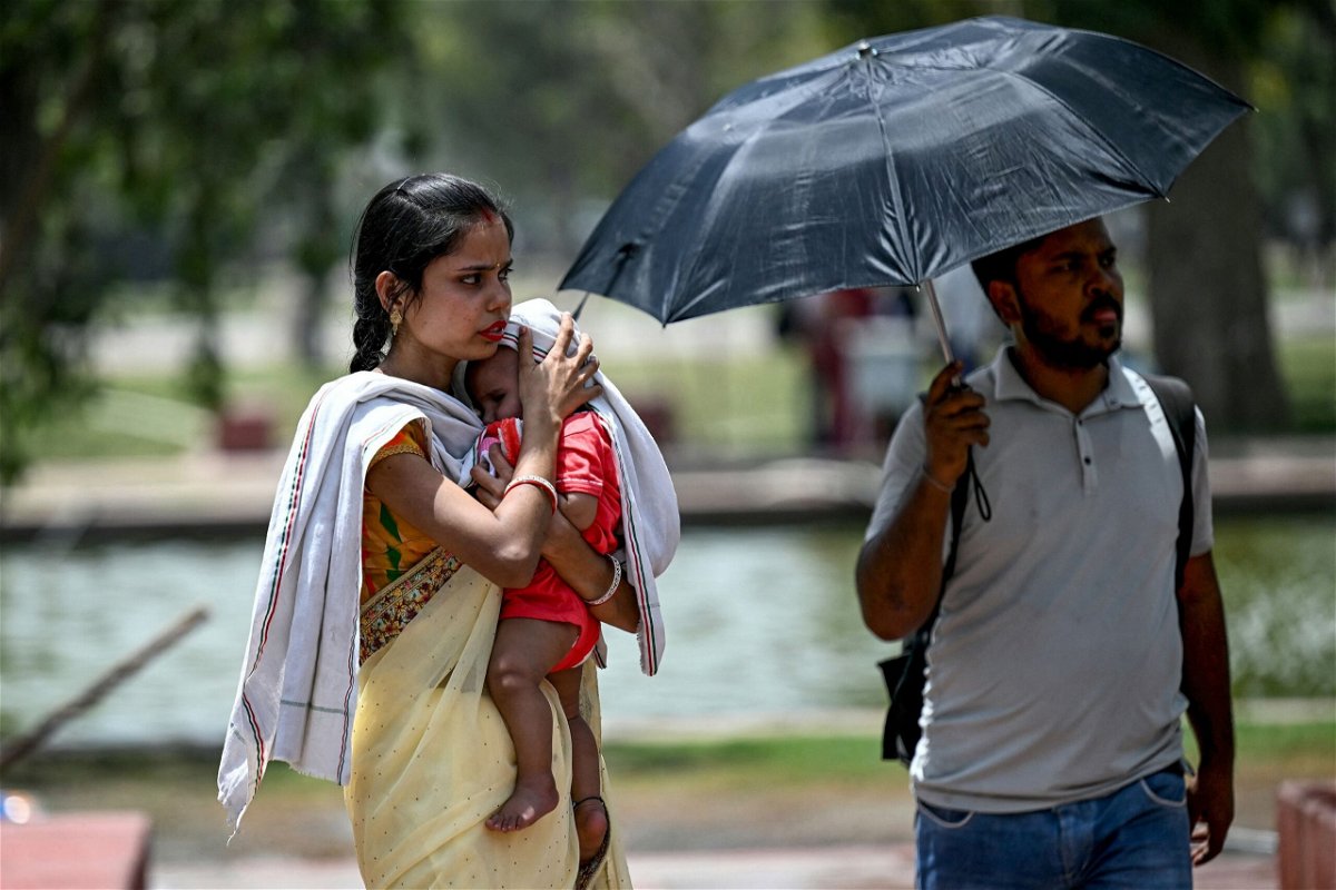 <i>Money Sharma/AFP/Getty Images via CNN Newsource</i><br/>A woman shields her child from the sun during a heat wave in New Delhi on Wednesday.
