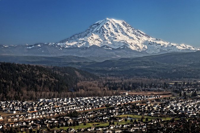 Mount Rainier, a snowcapped volcano, looms over Puyallup Valley near Orting, Washington. The prospect of a lahar — a swiftly moving debris flow caused by melting snow and ice typically during a volcanic eruption — poses a threat to surrounding communities.