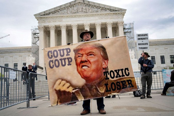 A demonstrator holds a sign outside the U.S. Supreme Court as the justices hear arguments on former President Trump's claim of presidential immunity over criminal charges over his efforts to overturn the 2020 presidential election results in Washington DC on April 25.