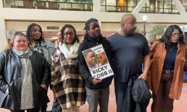 Family and activists for Ricky Cobb II stand with a sign saying "Justice for Ricky Cobb II" in Minneapolis