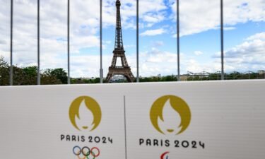 The Olympic rings and the Paralympic Games logo can be seen on a sign on a construction fence in front of the Eiffel Tower. The Olympic Games and Paralympics take place in France this summer.