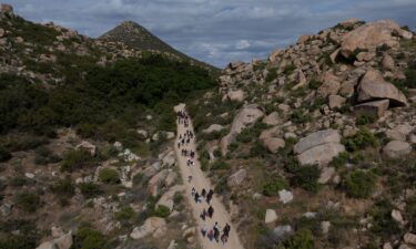 A drone view shows asylum seeking migrants from China and Turkey as they climb a hill while looking to surrender to immigration officials after crossing the border into the United States from Mexico in Jacumba Hot Springs