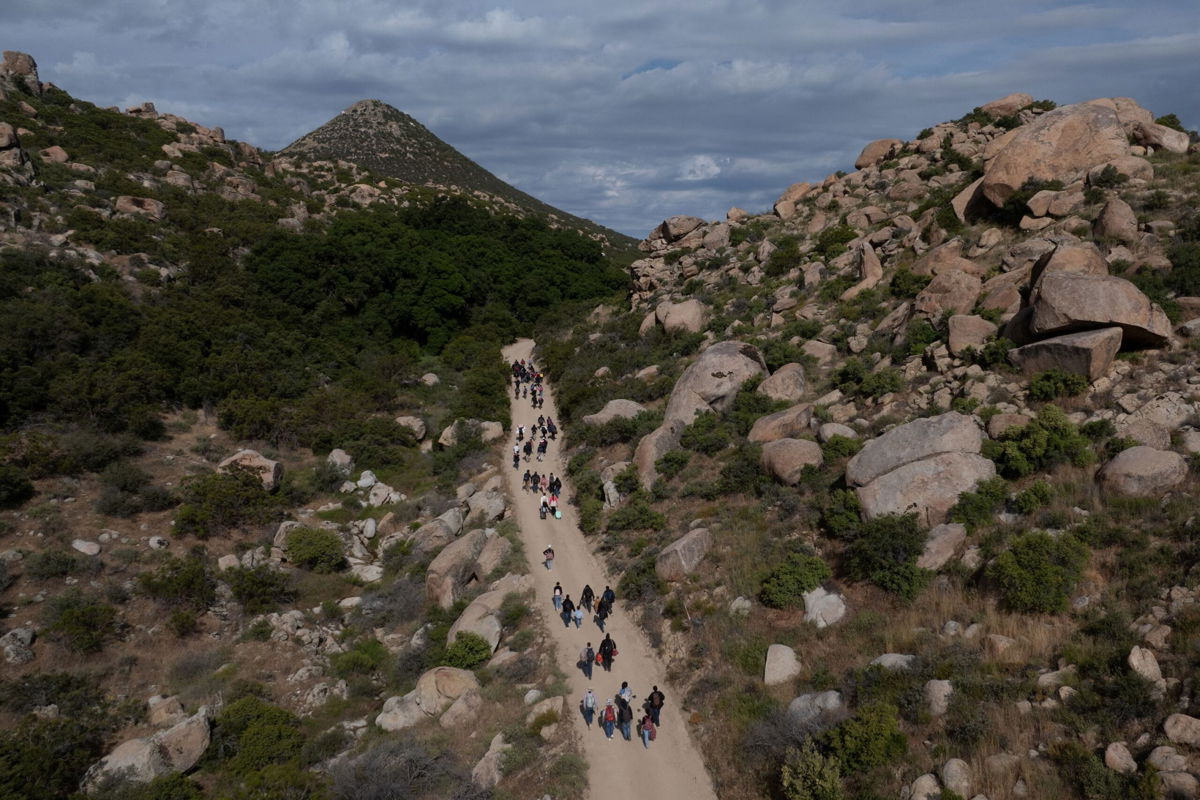 <i>Adrees Latif/Reuters/File via CNN Newsource</i><br/>A drone view shows asylum seeking migrants from China and Turkey as they climb a hill while looking to surrender to immigration officials after crossing the border into the United States from Mexico in Jacumba Hot Springs