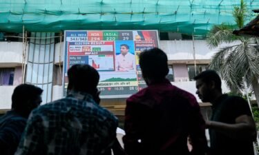 Pedestrians watch share prices on a digital broadcast outside the Bombay Stock Exchange (BSE) on the day of India's general election result in Mumbai on June 4.