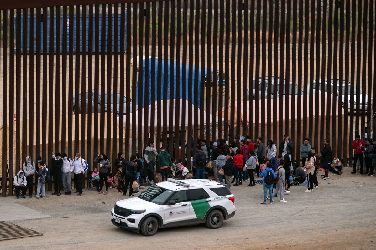 <i>Guillermo Arias/AFP/Getty Images via CNN Newsource</i><br/>Migrants and asylum seekers wait to be processed by the Border Patrol between fences at the US-Mexico border seen from Tijuana