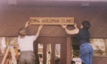 Two women hang a sign above the entrance of the Emma Goldman Clinic upon opening.