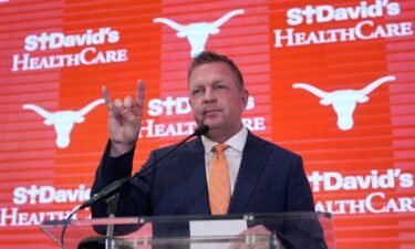 Jim Schlossnagle flashes a hook'em sign as he speaks at a news conference after he was introduced as the new NCAA college head baseball coach at Texas