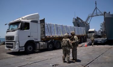 U.S. Army soldiers stand next to trucks arriving loaded with humanitarian aid at the U.S.-built floating pier Trident before reaching the beach on the coast of the Gaza Strip