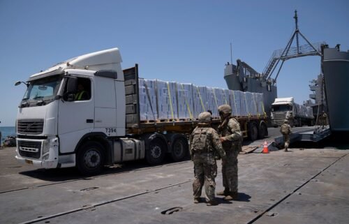 U.S. Army soldiers stand next to trucks arriving loaded with humanitarian aid at the U.S.-built floating pier Trident before reaching the beach on the coast of the Gaza Strip