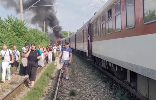 Smoke billows from a fire while people evacuate from a train