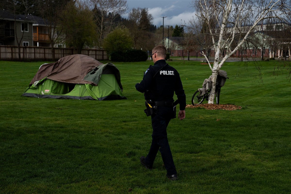 <i>Jenny Kane/AP via CNN Newsource</i><br/>A police officer walks to check on a homeless person on March 23