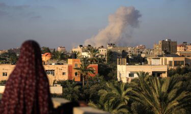 A Palestinian woman watches as smoke billows following an Israeli strike south of Gaza City