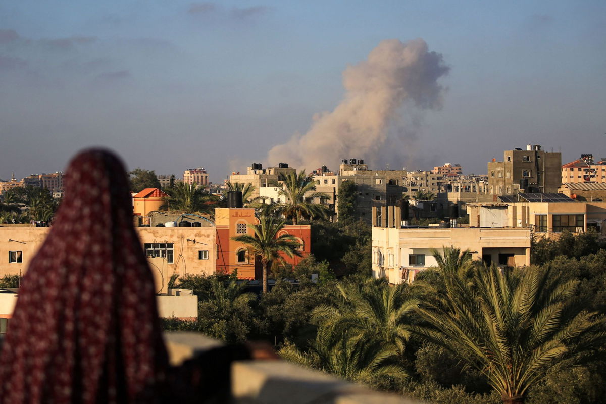 <i>Eyad Baba/AFP/Getty Images via CNN Newsource</i><br/>A Palestinian woman watches as smoke billows following an Israeli strike south of Gaza City